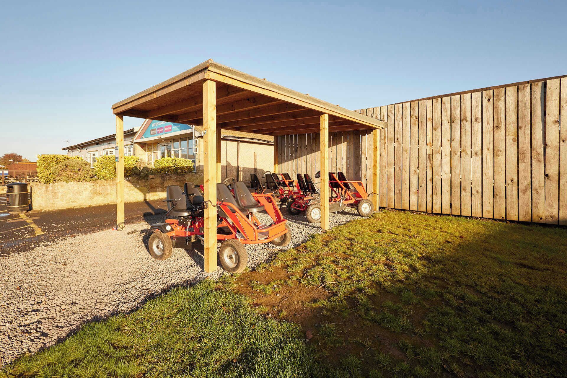 A covered outdoor seating area with lawn chairs and a wooden fence in the background.