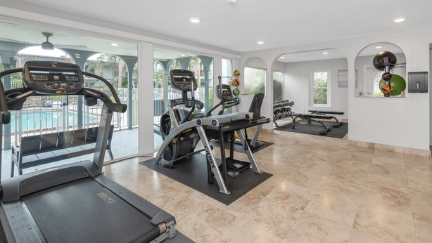 Ein modernes Fitnessstudio mit Laufbändern, Crosstrainern und Gewichtsbänken.