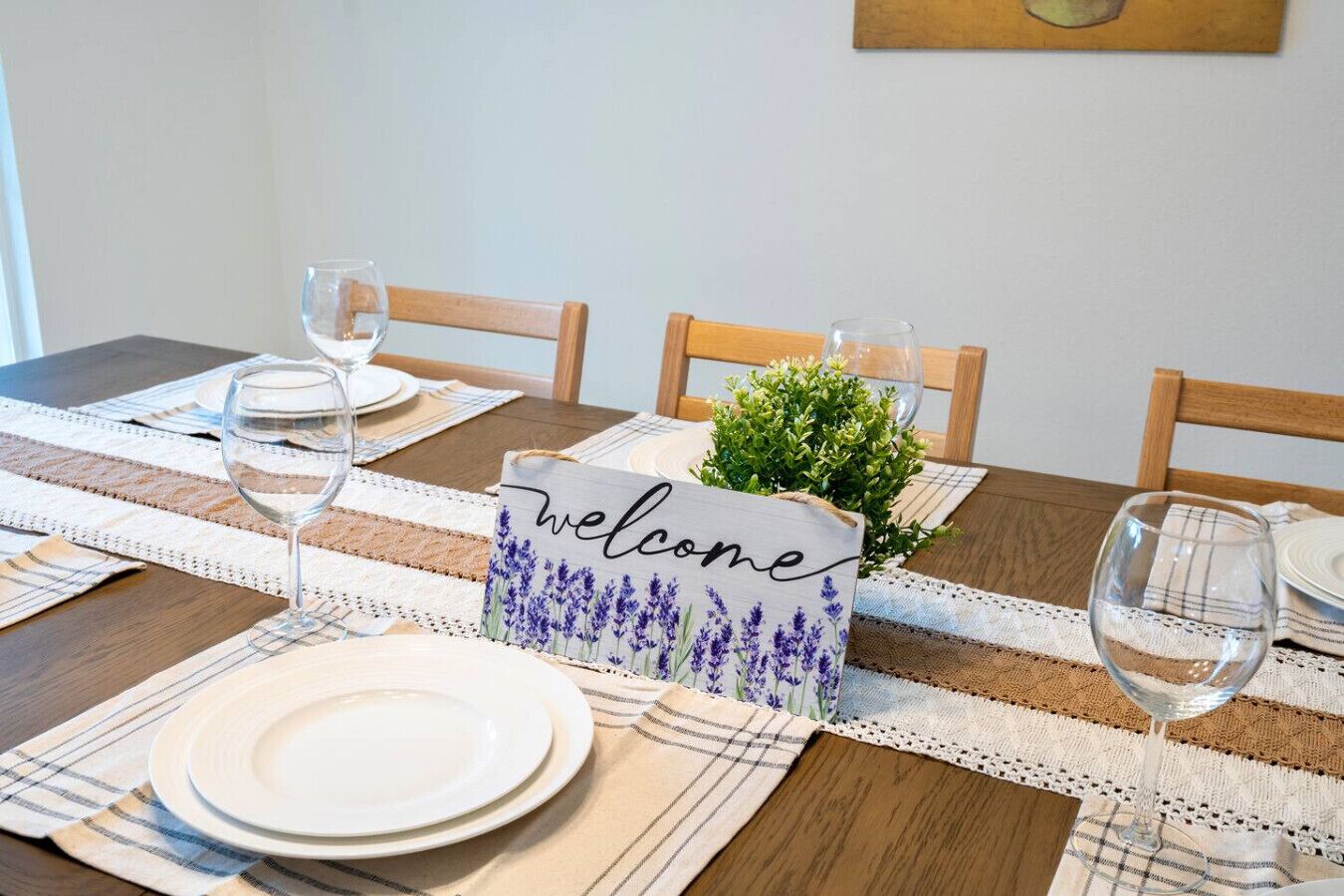 A dining table set with plates, glasses, and a 'welcome' sign with lavender flowers.