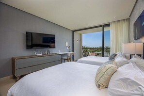 Ein modernes Hotelzimmer mit zwei Betten, einem Flachbildfernseher, einem Schreibtisch und einem großen Fenster mit Blick auf die Stadt.