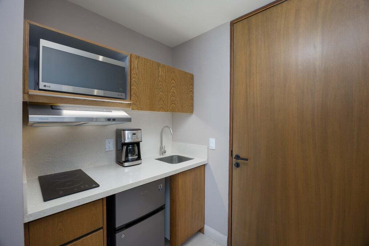 A compact kitchen with a microwave, coffee maker, and a built-in oven.