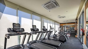 Une salle de sport équipée de tapis de course, de vélos elliptiques et de matériel de musculation.