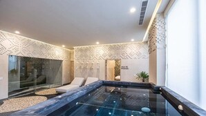 Un moderno espacio de spa con jacuzzi, sillones reclinables y sala de masajes.