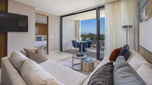 Een moderne hotelkamer met een grote bank, een klein bijzettafeltje en een balkon met een eethoek.