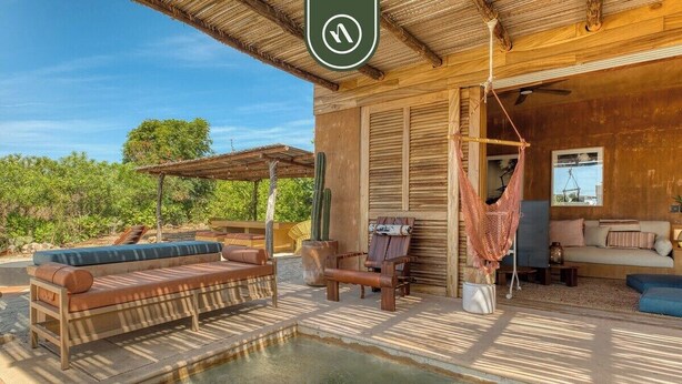 Une cabane en bois avec une piscine, un espace salon extérieur et un hamac.