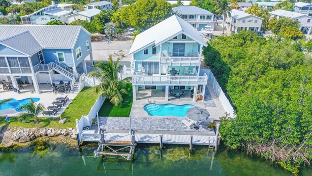 A waterfront property with a swimming pool, a dock, and a covered patio area.