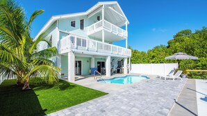 A two-story house with a swimming pool, a covered patio, and a well-maintained lawn.