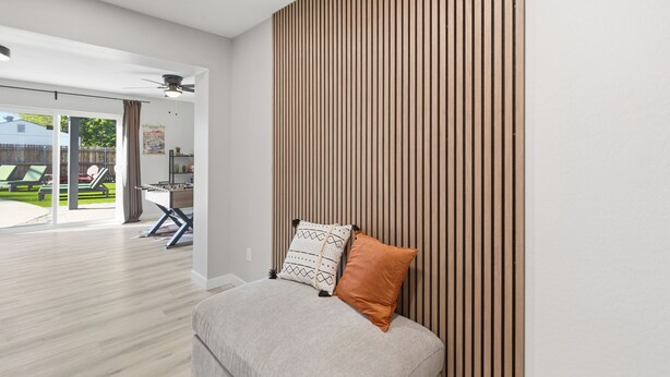 Ein modernes Wohnzimmer mit einer Couch, Kissen und einer Wand aus Holzleisten.