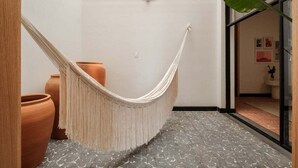 Un fauteuil suspendu dans une pièce décorée de pots en terre cuite et d’une grande plante.
