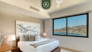 Une chambre à coucher moderne avec un grand lit, une vue sur la mer et un tableau accroché au mur.