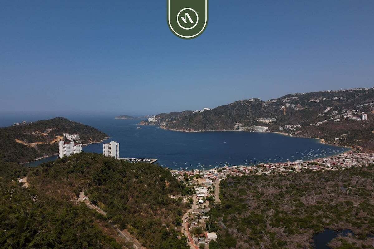 Eine Küstenstadt mit Gebäuden, blauem Meer und hügeliger Landschaft.