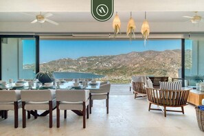 A dining area with a table set for four, chairs, and a view of a mountainous landscape through large windows.