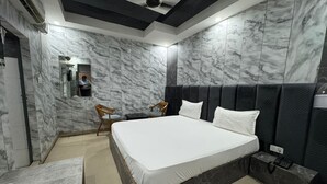 A modern bedroom with a large bed, marble walls, and a dark headboard. - Hotel Natraj A Boutique Hotel (Haridwar)