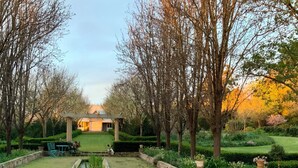 A swimming pool with a stone deck, surrounded by a well-manicured lawn and trees.