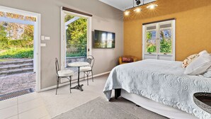 A bedroom with a bed, a chair, a table, and a window.