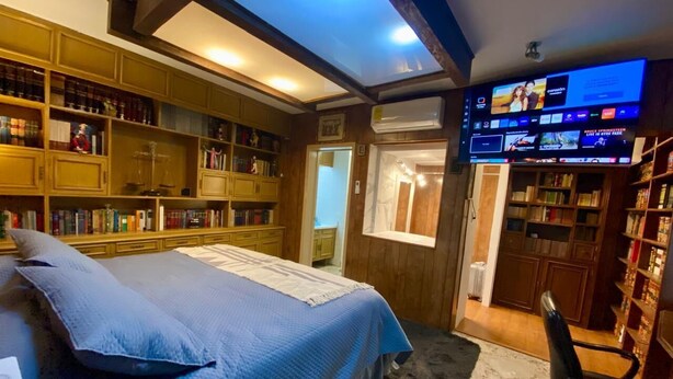 Ein Schlafzimmer mit einem großen Bett, Holzregalen, einem Schreibtisch und einem Fernseher.