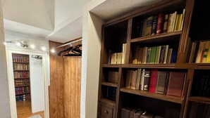 Ein Flur mit Holzboden, einem Spiegel und einem Bücherregal voller Bücher.