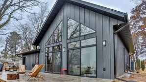 A modern house with large windows and a patio area with outdoor furniture. - Wausau Chalet- 3BR w/ Dock & Lake w/ River Access (Wausau)