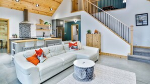 A modern loft-style living space with a kitchen, dining area, and a staircase leading to an upper level. - Wausau Chalet- 3BR w/ Dock & Lake w/ River Access (Wausau)