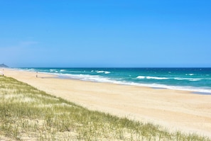 Una spiaggia con cielo sereno, riva sabbiosa e onde.