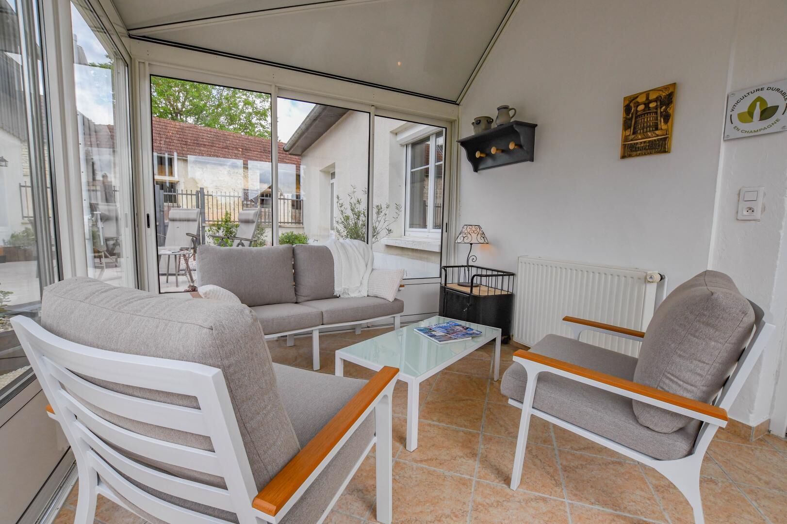 Une pièce lumineuse, avec un canapé, des fauteuils, une table basse et une vue sur l’extérieur.