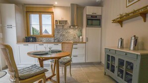 A kitchen with a dining table, chairs, a coffee machine, an oven, and a cabinet with jars. - La Ferm'Hier - BALNOT SUR LAIGNES (BALNOT SUR LAIGNES)
