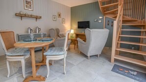 A cozy living room with a dining area, a sofa, a TV, and a wooden staircase. - La Ferm'Hier - BALNOT SUR LAIGNES (BALNOT SUR LAIGNES)