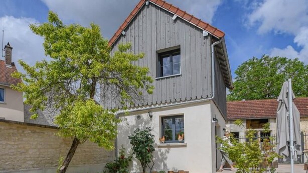 A two-story house with a sloped roof, a small front porch, and a gravel driveway. - La Ferm'Hier - BALNOT SUR LAIGNES (BALNOT SUR LAIGNES)