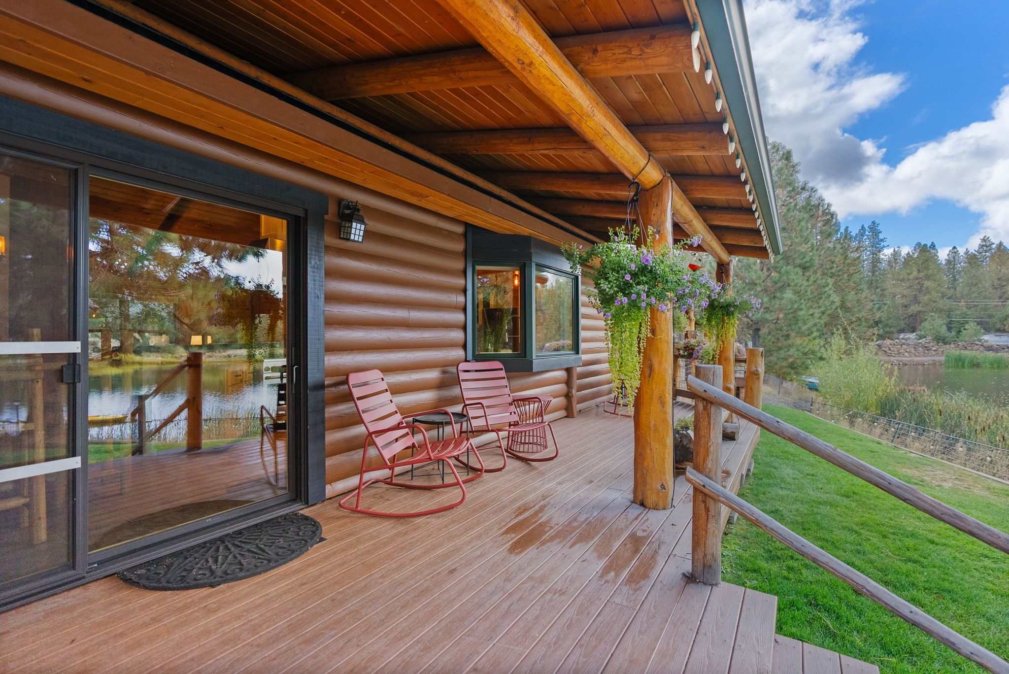 Una terraza de madera con mobiliario exterior y vista a un lago.