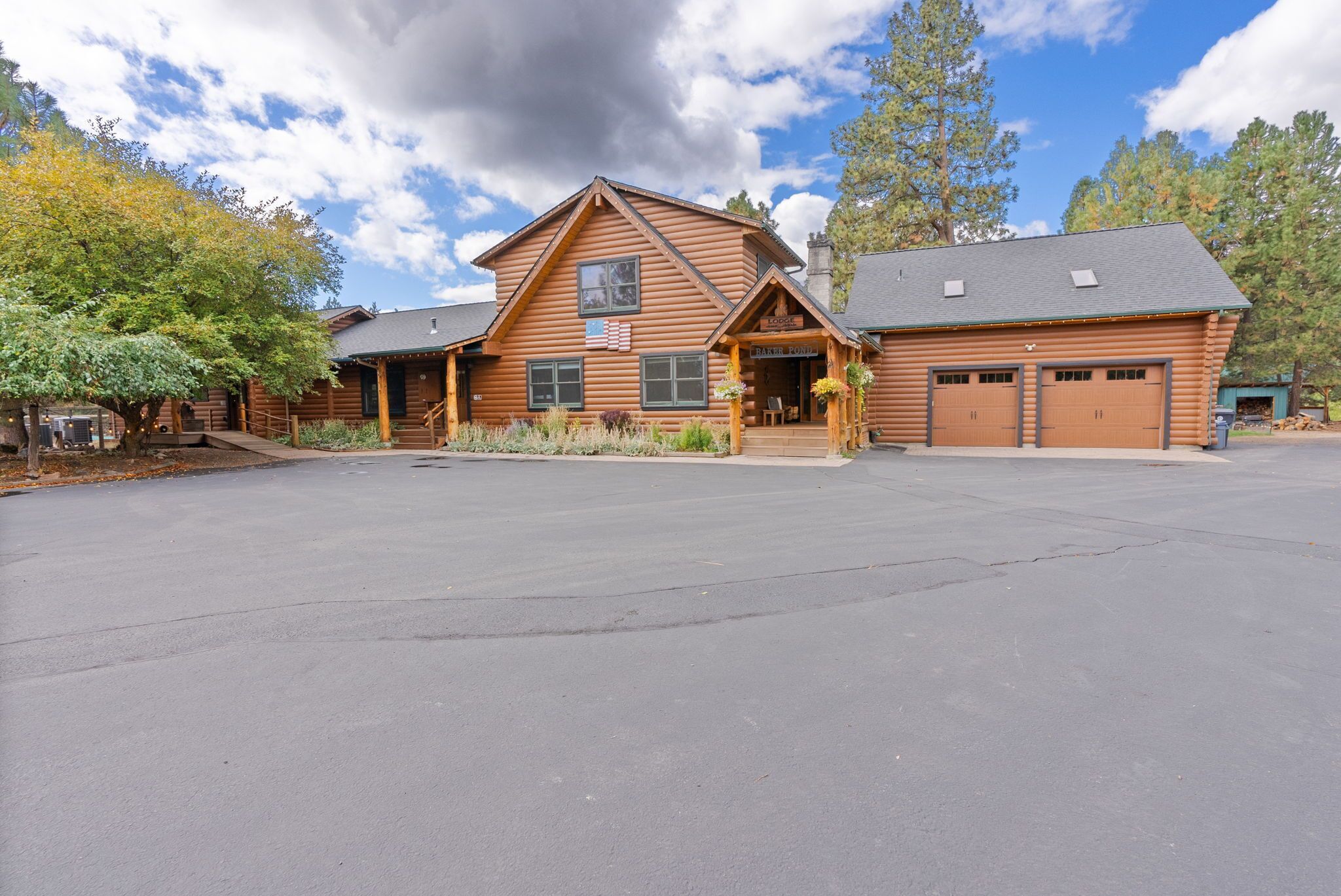 A log cabin with a large garage and a covered porch.
