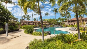 Um resort com piscina cercada por palmeiras e vegetação exuberante.