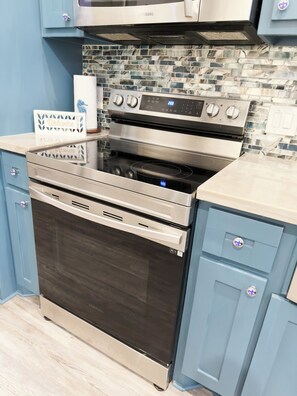 A kitchen with a stainless steel oven, a microwave, and a tiled backsplash.