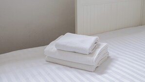 A neatly made bed with white bedding and a folded white towel on top. - Mokotów Urban Comfort Apartment (Warszawa)