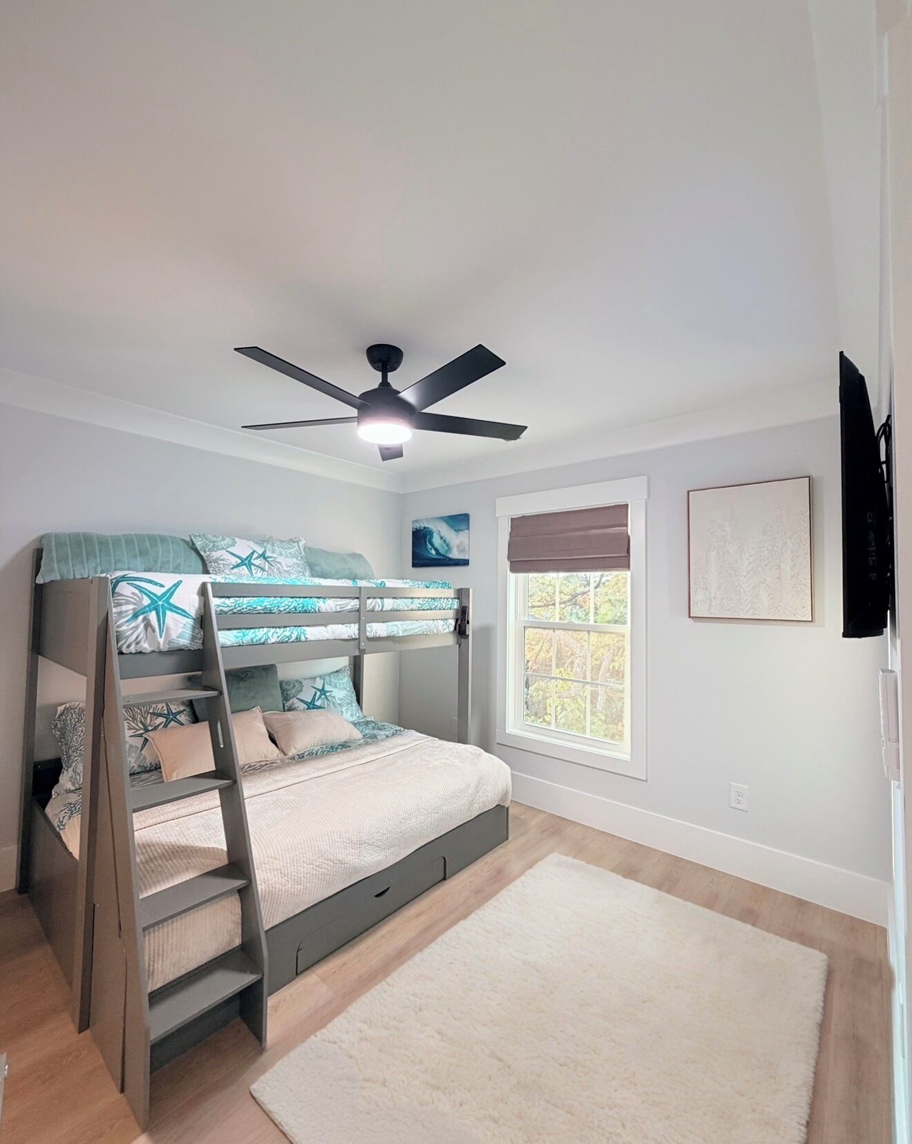 Ein Schlafzimmer mit Etagenbett, Deckenventilator, Fenster mit Jalousien und Teppichboden.