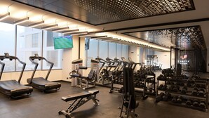 Une salle de sport équipée de tapis de course, d’appareils de musculation et d’haltères.