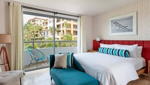 A hotel room with a large bed, a sofa, a chair, and a view of a building through a glass door. - Ocean Front Penthouse in beautiful Cabo San Lucas on Medano Beach (Cabo San Lucas)