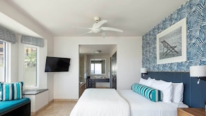 A bedroom with a bed, a TV, a bench, and a patterned wall. - Ocean Front Penthouse in beautiful Cabo San Lucas on Medano Beach (Cabo San Lucas)