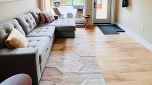 Un salon spacieux avec un grand canapé d’angle, un plancher en bois et une lucarne.