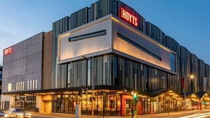 Un hôtel moderne, reconnaissable à son grand panneau « HOYTS », à ses larges fenêtres et à son entrée bien éclairée.