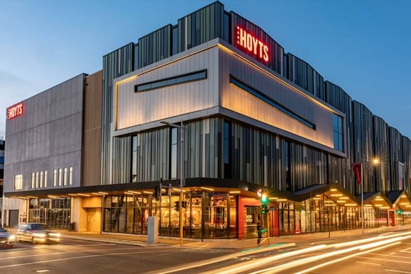 A modern hotel with a prominent 'HOYTS' sign, large windows, and a well-lit entrance. - Modern CBD Studio w/ King Bed | Ground Floor Ease (Christchurch)