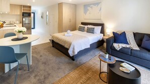 A modern hotel room with a bed, a sofa, a dining area, and a kitchen. - Modern Studio Near Stadium, Dining & City Fun (Christchurch)