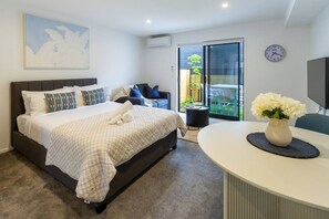 Een moderne slaapkamer met een groot bed, een nachtkastje, een stoel en uitzicht op de omgeving door een glazen schuifdeur.