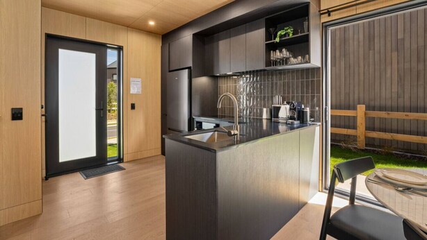 Eine moderne Küche mit einer zentralen Kochinsel, Edelstahlgeräten und einer Wand aus Holz.