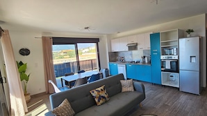 A modern living area with a sofa, dining table, and kitchen with blue cabinets. - T3 Le Myrte sea & mountain view ideally located (PROPRIANO)
