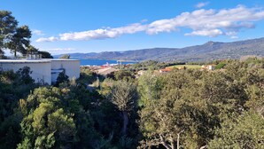 A coastal landscape with a building overlooking the sea, surrounded by dense greenery and hills in the background. - T3 Le Myrte sea & mountain view ideally located (PROPRIANO)