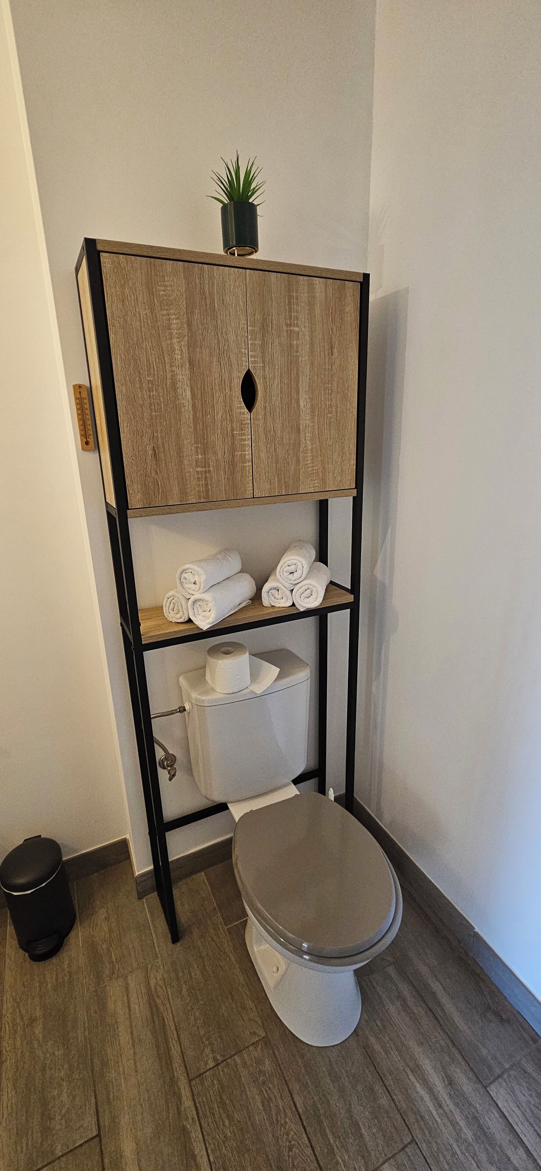 Un baño moderno con tocador de madera, papel higiénico y toallas.