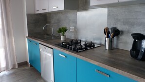 A modern kitchen with a gas stove, a coffee machine, and a potted plant. - T3 Le Myrte sea & mountain view ideally located (PROPRIANO)