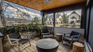 A covered outdoor seating area with wooden flooring, a round table, and two chairs. - Lofts on Main - Ravenel (Highlands)
