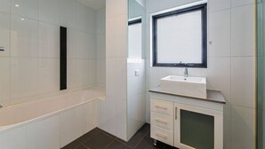 Ein modernes Badezimmer mit Badewanne, Waschbecken und Spiegel.