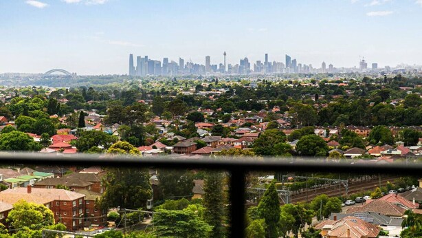 Eine Stadtansicht mit einem dicht bebauten Wohngebiet im Vordergrund und einer Skyline aus Hochhäusern im Hintergrund.